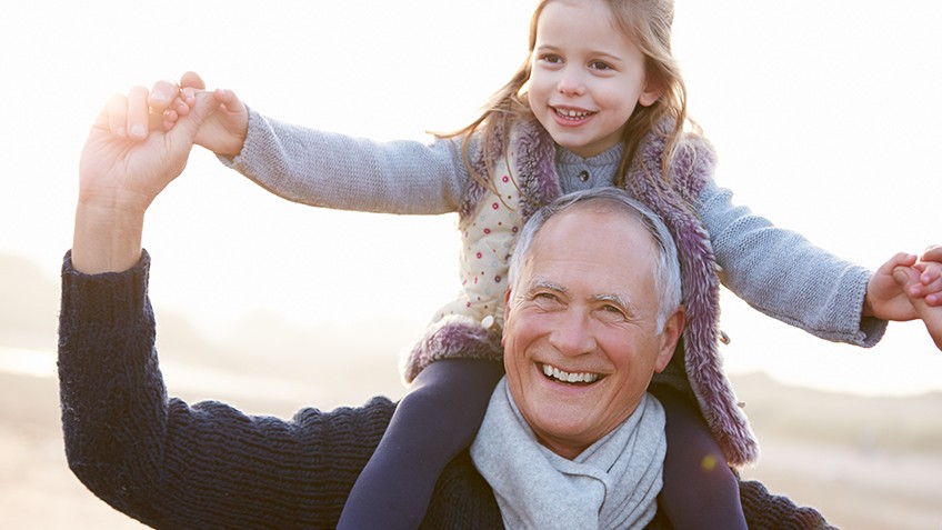 A smiling grandfather and grandchild on his shoulder.