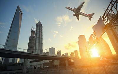 Skyscraper buildings, an airplane on the sky at sunset.