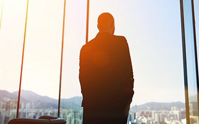 A man standing backward, looking at the glass window.