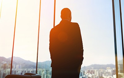 A man standing backward, looking at the glass window. 