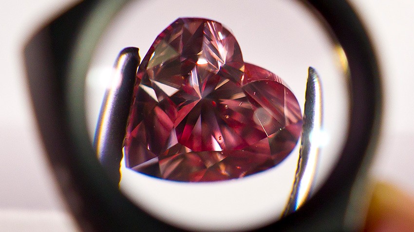 A heart-shaped diamond examined over a lens.