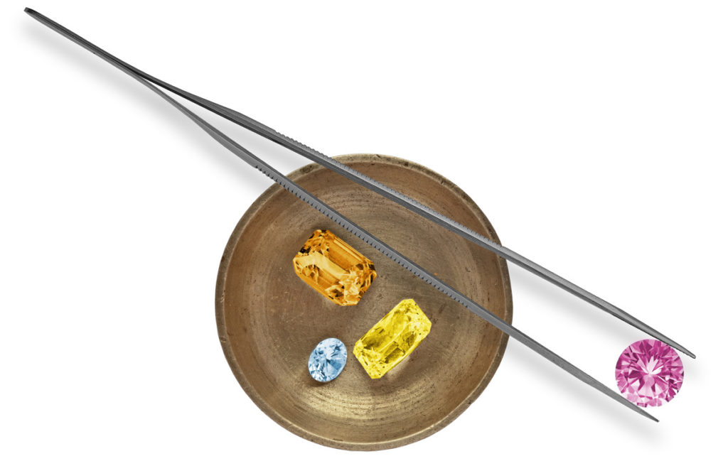 Coloured diamonds in a small dish with tweezers resting on top.